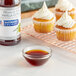 A cupcake with white frosting and a bottle of brown liquid vanilla extract.