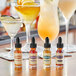 A table with bottles of Scrappy's Bitters next to glasses of different cocktails.