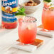 A glass of Torani sugar-free watermelon flavoring with a slice of watermelon on the rim.