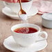A hand pouring Splenda sugar and sweetener blend into a cup of tea.