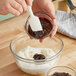 A person mixing chocolate flavoring paste in a bowl.
