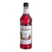 A close up of a bottle of Monin Premium Dragon Fruit flavoring syrup with red liquid inside.