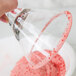 A hand holding a glass with a red rim using Rokz Cranberry Cosmo cocktail rimming sugar.