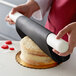 A person using Satin Ice ChocoPan black covering chocolate to cover a cake.