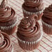 A chocolate cupcake with chocolate frosting on a cooling rack.