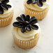 A cupcake with Satin Ice ChocoPan black modeling chocolate flowers on top.