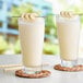 Two glasses of banana smoothies with straws on a white background.