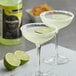 Two glasses of Regal Margarita with lime slices and a bottle of Regal Margarita on a table.