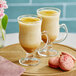 A wooden tray with two glass cups of Dona Turmeric Golden Latte and cookies.