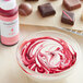 A bowl of red and white swirls with chocolate and Chefmaster Pink Oil-Based Candy Color on a white background.