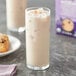 A glass of Oregon Chai Organic Slightly Sweet Chai Tea Latte over ice with a plate of cookies.