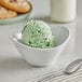 A bowl of pistachio ice cream with a spoon and cookies.