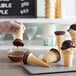 A person pouring Phillips chocolate sauce into an ice cream cone.