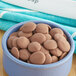 A bowl of Cacao Barry milk chocolate pistoles on a table.