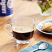 A glass of Lavazza In Blu ground espresso on a table with a spoon.
