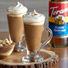 Two glasses of coffee with Torani Classic Hazelnut syrup, whipped cream, and nuts.