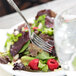 A Oneida Rosewood stainless steel fork in a bowl of salad.