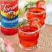 A glass of strawberry Torani syrup drink with a rosemary sprig.