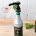 A close-up of a Monin Mint Concentrated Flavor bottle on a bar counter next to a glass of minty liquid.