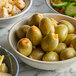 A bowl of Belosa Cream Cheese & Habanero Stuffed green olives on a table with other food.