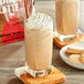 A glass of DaVinci Gourmet Tahitian Vanilla Chai Tea with whipped cream and cookies on top.