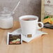 A cup of Bromley Tuscan Lemon herbal tea on a table with a packet of tea.