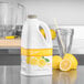 A white jug of Torani Lemonade Smoothie Mix on a white counter.