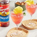 Two glasses of pink hibiscus drinks with flowers on top.