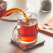A person pouring Davidson's Organic English Breakfast loose leaf tea into a glass mug.