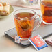 A glass mug of Bromley tea with a tea bag in it on a table.