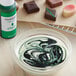 A bowl of white liquid with green and black swirls.