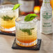Two glasses of drinks with mint leaves on top.