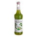 A green Monin bottle of pistachio flavoring syrup with a white label.
