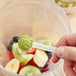 A hand holding a white spoon with Add A Scoop Premium Matcha Green Tea Powder in it.