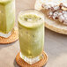 A glass of green liquid next to cookies.
