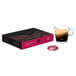A box of Nespresso Professional Colombia Organic Single Serve Coffee Capsules on a table next to a glass of brown liquid.