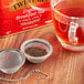 A cup of Twinings Earl Grey tea with a metal mesh strainer.