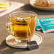 A glass cup of Stash Jasmine Blossom green tea with a tea bag in it.