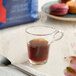 A glass cup of Lavazza Top Class espresso on a table with a spoon.