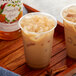 A cup of iced coffee with a bottle of Monin Pumpkin Spice syrup on a table.