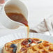 A person pouring Butternut Mountain Farm Vermont maple syrup on a waffle.