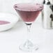 A martini glass with a purple drink rimmed with Rokz Pomegranate Cocktail Rimming Sugar.