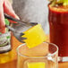 A person using scissors to cut a Van Holten's Pickleback Pickle Juice Mixer in a glass.