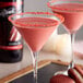 A martini glass filled with a pink DaVinci Gourmet Classic Red Velvet Cake drink.