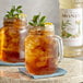 A glass jar of brown Monin Ginger syrup with ice cubes.