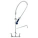 A T&S chrome pre-rinse faucet with a blue ergonomic spray valve and flexible hose.