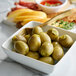 A bowl of Belosa Dill Pickle Stuffed Queen Olives on a table with other food.