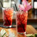 A glass of Monin hibiscus flavored red liquid with ice and a straw.