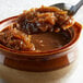 A spoon with Regal Onion Powder lifting up a bowl of caramelized onions.