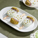 A plate of pistachio-flavored ice cream bars partially dipped in chocolate and sprinkled with chopped pistachios.